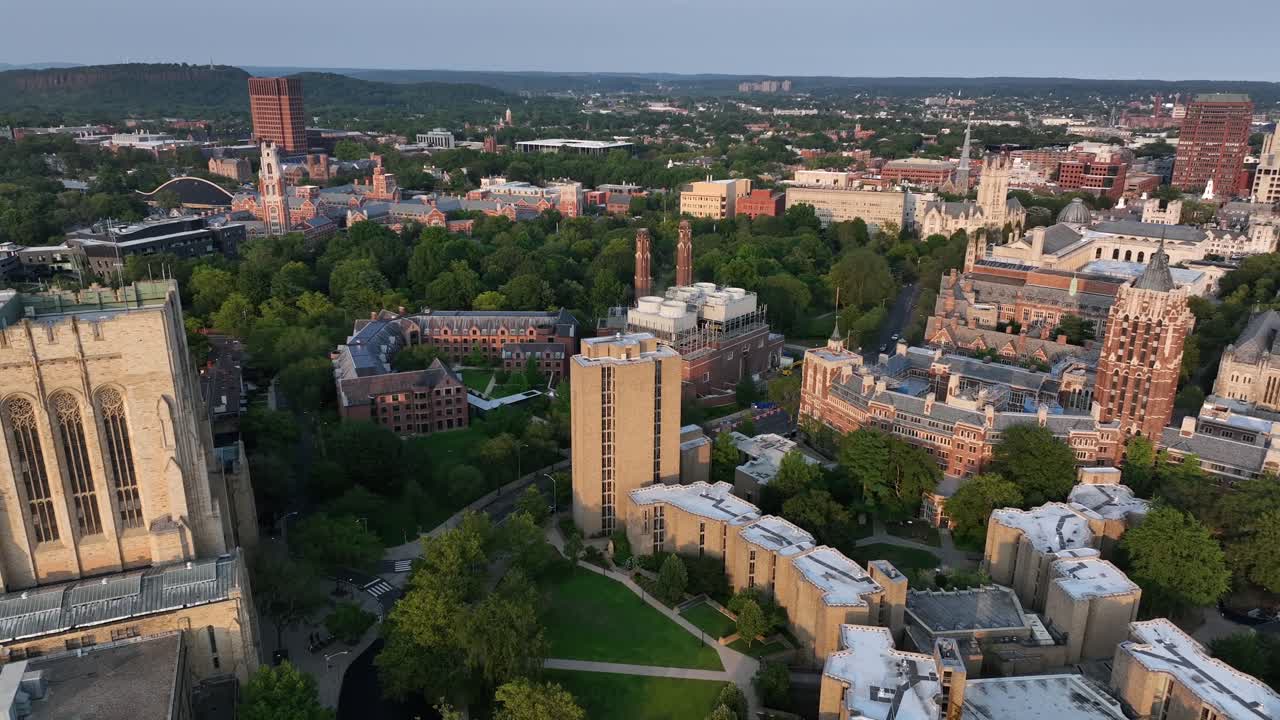 Aerial view of New Haven, Connecticut, showing Yale University’s historic campus with Gothic architecture, green spaces and surrounding urban skyline. Sunset time in summer. Wide shot