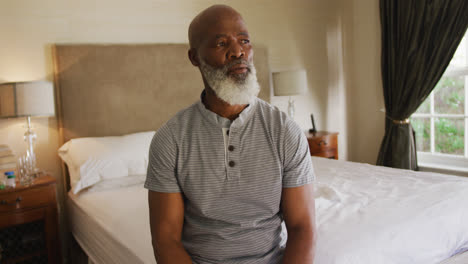 un anciano afroamericano pensativo sentado en la cama en casa