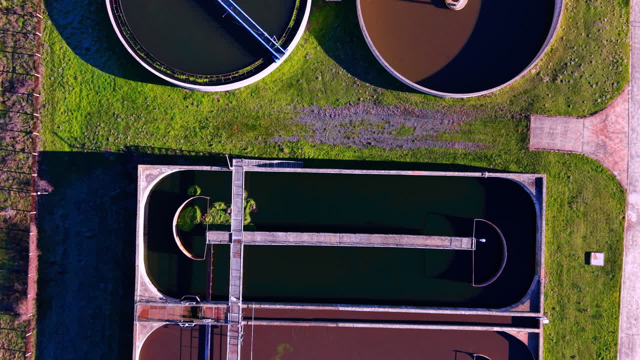 Round concrete clarifier tanks with water during purification process. Top down view of sedimentation tanks at plant