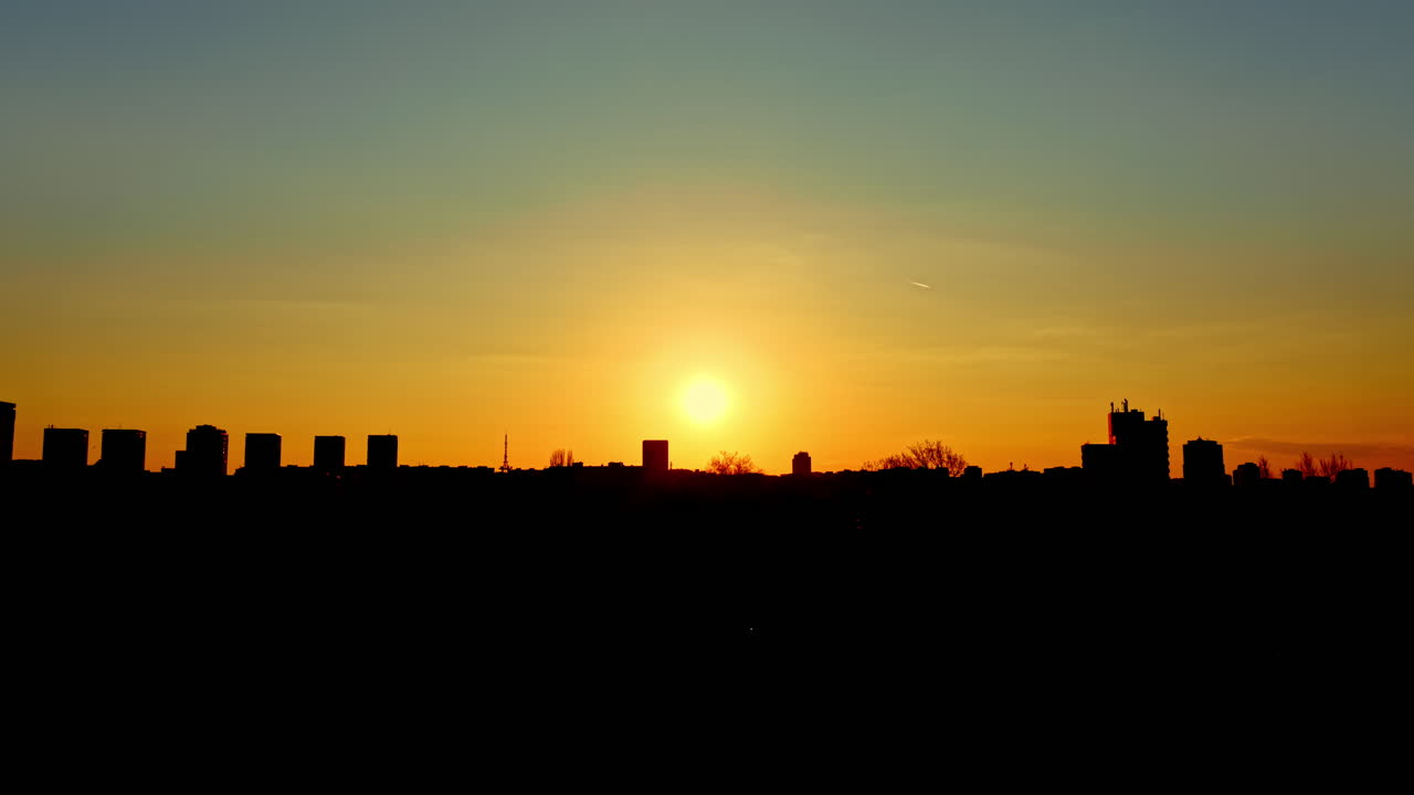 Puesta de sol sobre el horizonte de la ciudad con edificios y árboles en silueta
