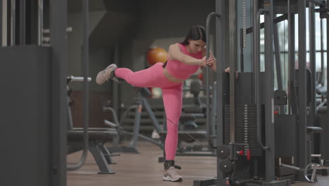 a young woman lifts her leg in a crossover to train her thigh and leg muscles. buttocks training. a professional female athlete does leg exercises