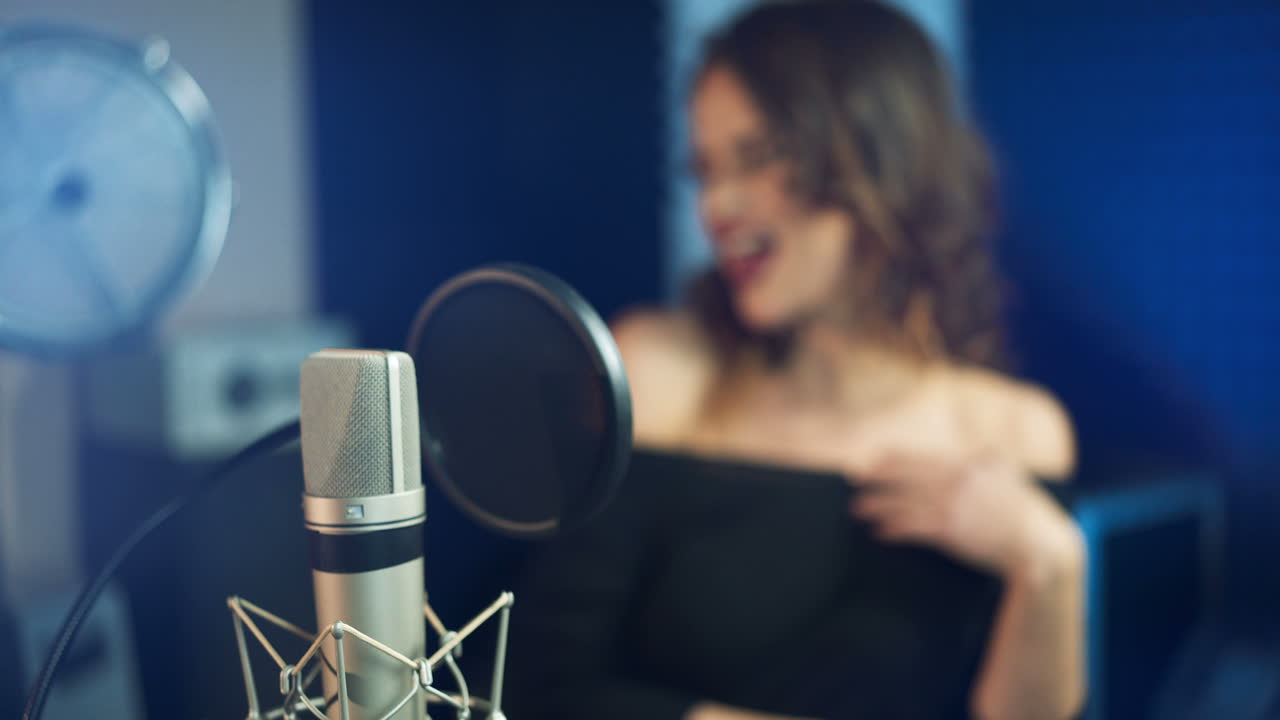 Professional microphone in the recording studio. Singing woman in the background