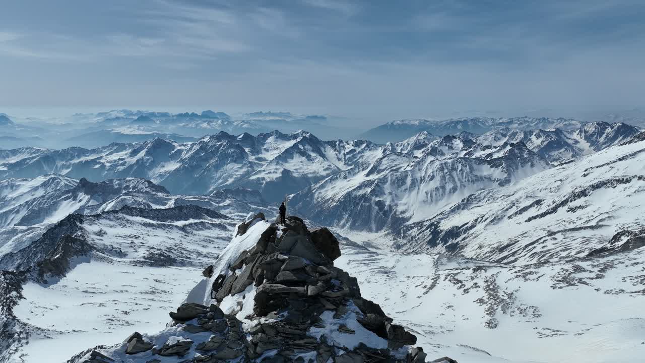 montañero en una cumbre rocosa en los alpes en un soleado día de invierno