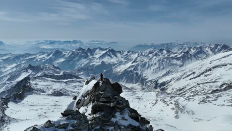 Mountaineer-on-a-rocky-summit-in-the-Alps-on-a-sunny-winter-day