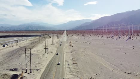 interminable carretera americana y enorme granja de turbinas eólicas en la zona del desierto, vista aérea de drones