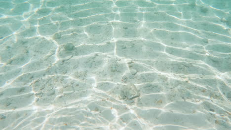 cinematic 4k 120fps slow motion shot of water caustics in the ocean with a sandy ocean floor on a bright and sunny day