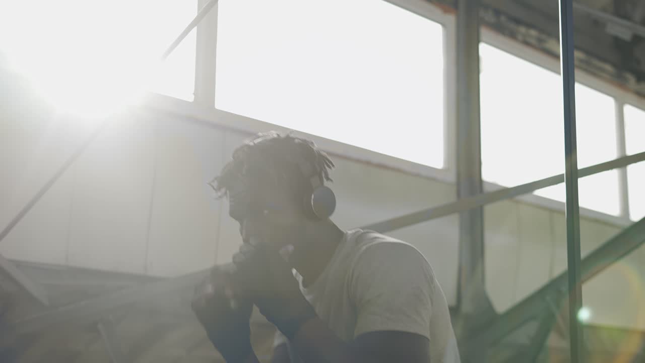 boxeador masculino practicando shadowboxing alrededor de las estructuras metálicas en interiores, bengalas de lentes