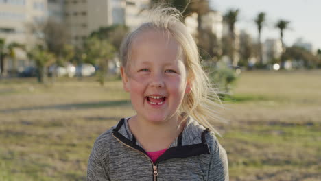 retrato de uma linda menina loira sorrindo feliz desfrutando de um dia de verão relaxado em um parque urbano ao pôr do sol em câmera lenta