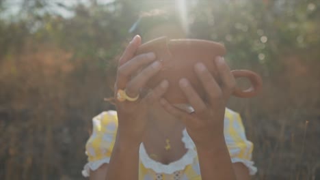 Close-up-of-a-young-woman-gluing-back-together-a-ceramic-cup-in-a-dry-field