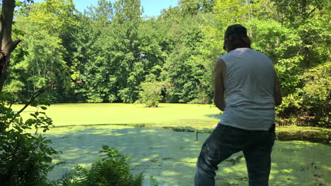 man fishing in a pond casting and reeling in