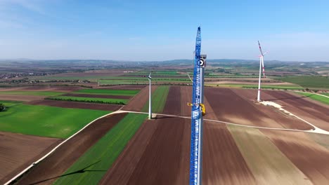 Large-Crane-On-A-Wind-Turbine-Construction-Site-In-Summer---aerial-shot