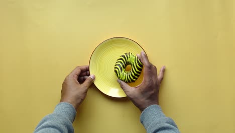 close up of a chocolate glazed donut on a yellow plate