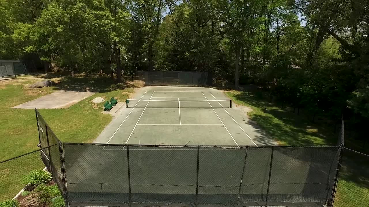 Rotating aerial shot of an empty tennis court on a sunny summer day