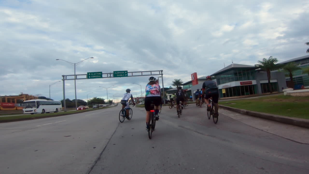 도로를 달리는 자전거 그룹이 건물 앞부분으로 변합니다.