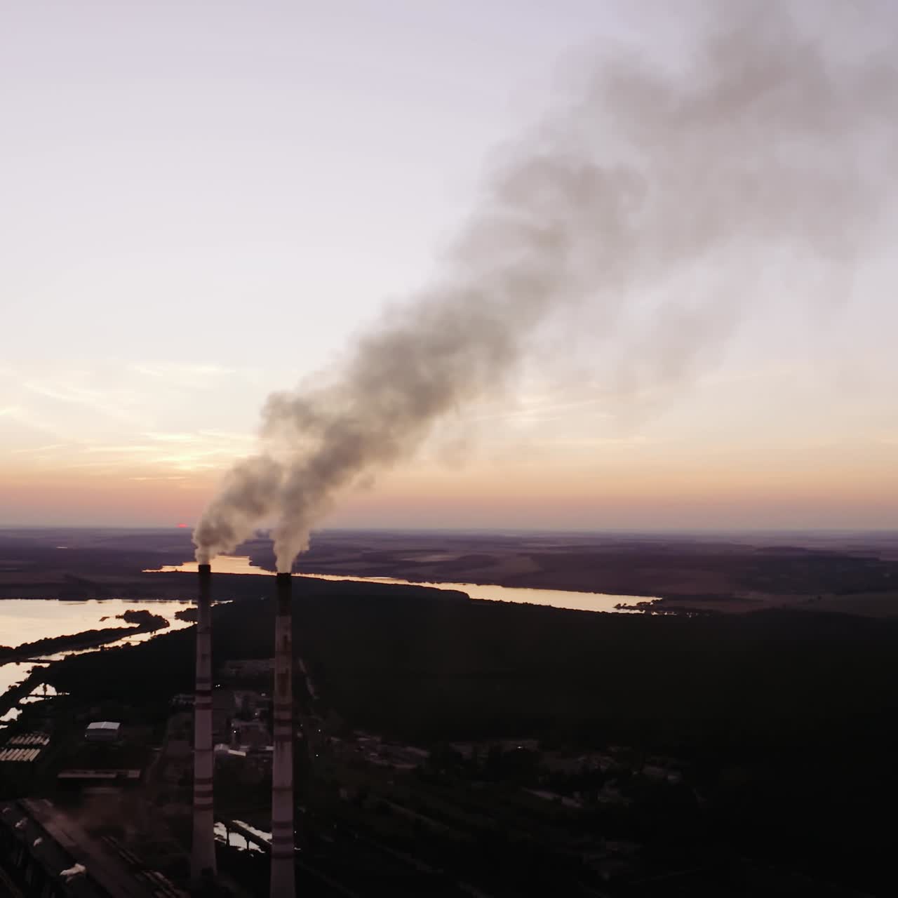 Industrial factory in nature in the evening. Chemical smoke from the factory chimneys. Concept of environmental pollution.