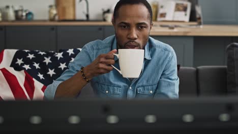 Vista-Frontal-Del-Contenido-Hombre-Negro-Bebiendo-Y-Viendo-Televisión.