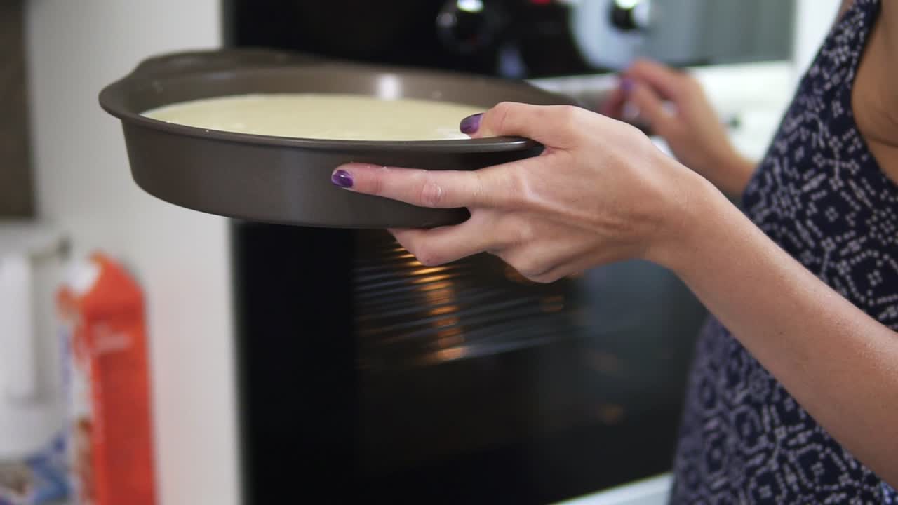 Close up of and unrecognizable woman choosing the temperature in the oven and putting a pie in a gray from into it. Slow Motion