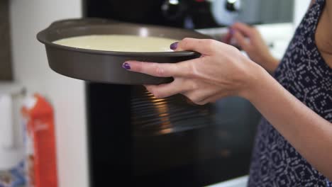 cerca y mujer irreconocible eligiendo la temperatura en el horno y poniendo un pastel en un gris de en él. cámara lenta