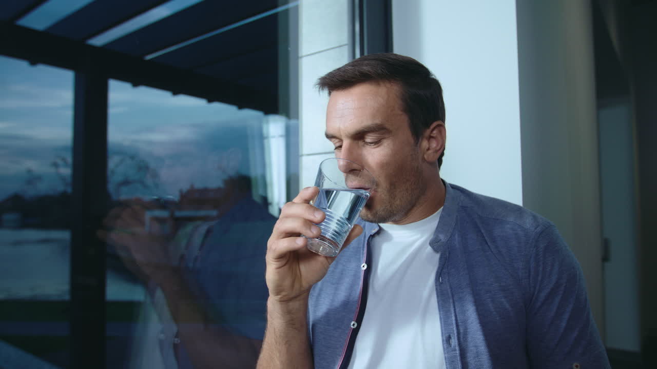 Relaxed business man drinking water near panoramic window