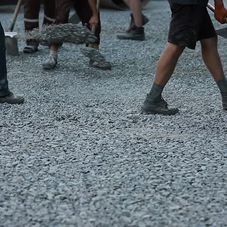workers throw gravel with shovels