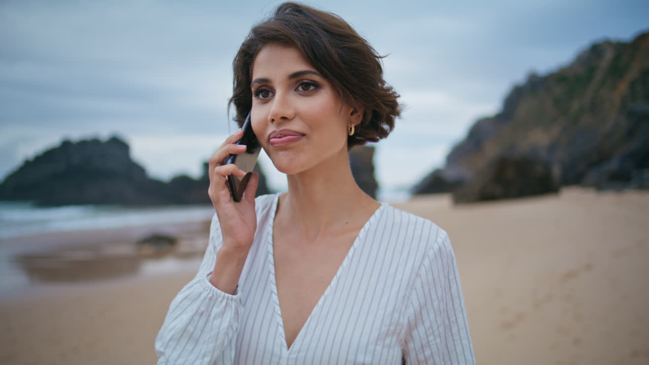 Smiling woman calling beach on cloudy day closeup. Relaxed girl talk smartphone