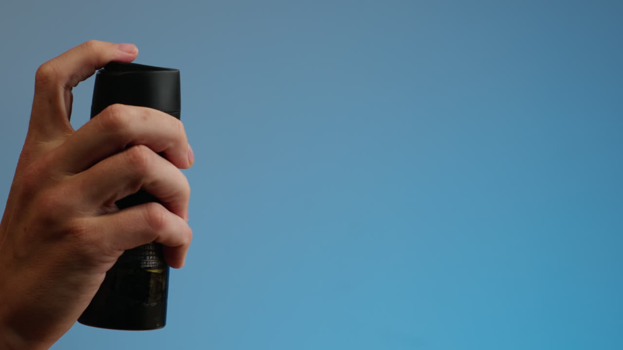 Young man applying perfume to skin in the dark, close up of spraying deodorant luxury perfume.