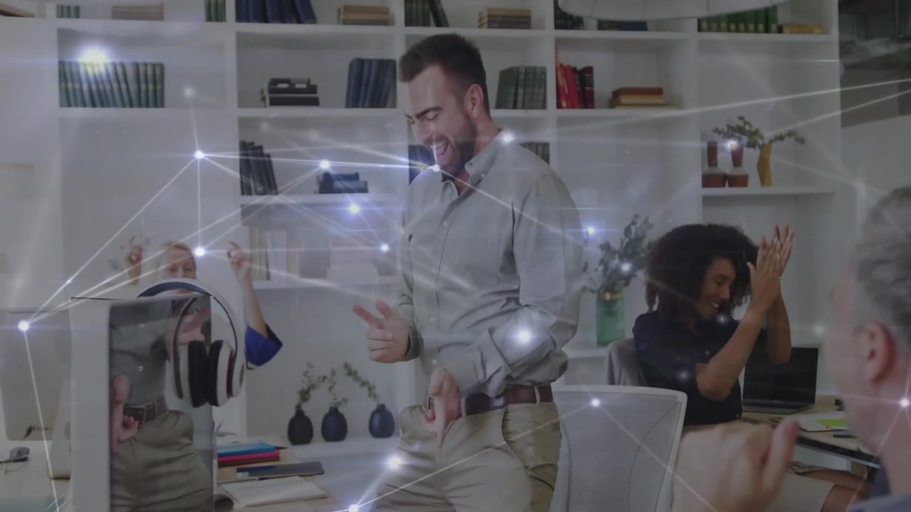 Male employee standing from desk celebrating win in business, glowing nodes linking over team