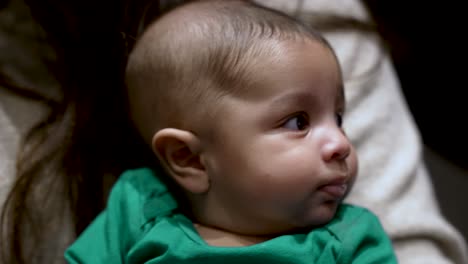 close up of adorable uk bangladeshi baby in festive green top being gently rocked in arms