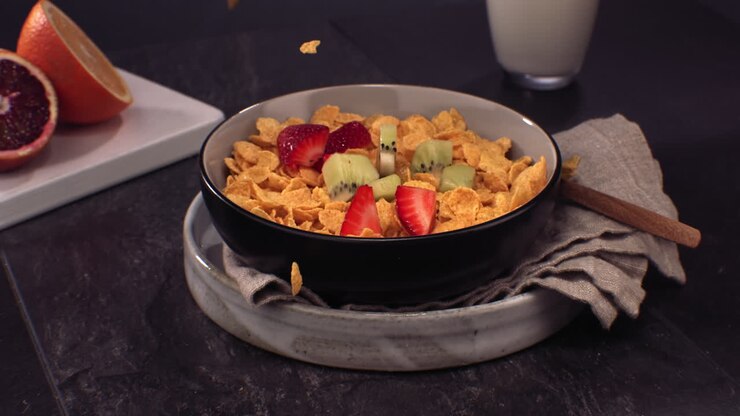 CÁMARA LENTA SÚPER CÁMARA LENTA. Fresas y kiwis frescos en rodajas cayendo en un tazón de cereales. Grabado con cámara de alta velocidad a 420 FPS.
