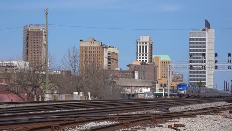 el tren de pasajeros de la ciudad de nueva orleans sale de birmingham alabama con el fondo del horizonte de la ciudad