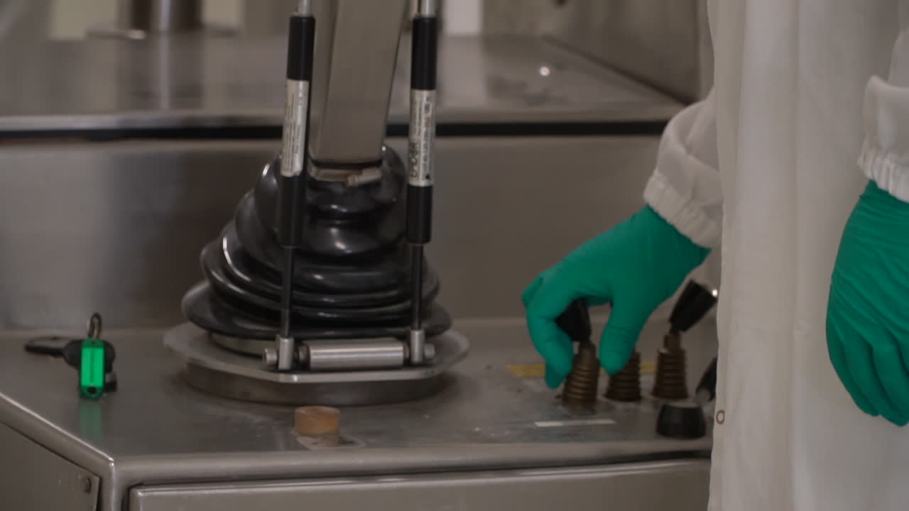 Medical laboratory worker operates pharma lab stainless steel machine, close up