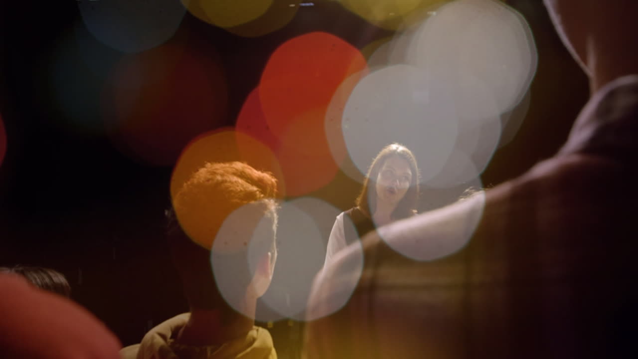 Business woman presenting on dark stage, with animated bokeh lights floating above audience