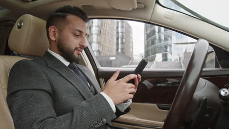 mixed-race driver in suit using smartphone