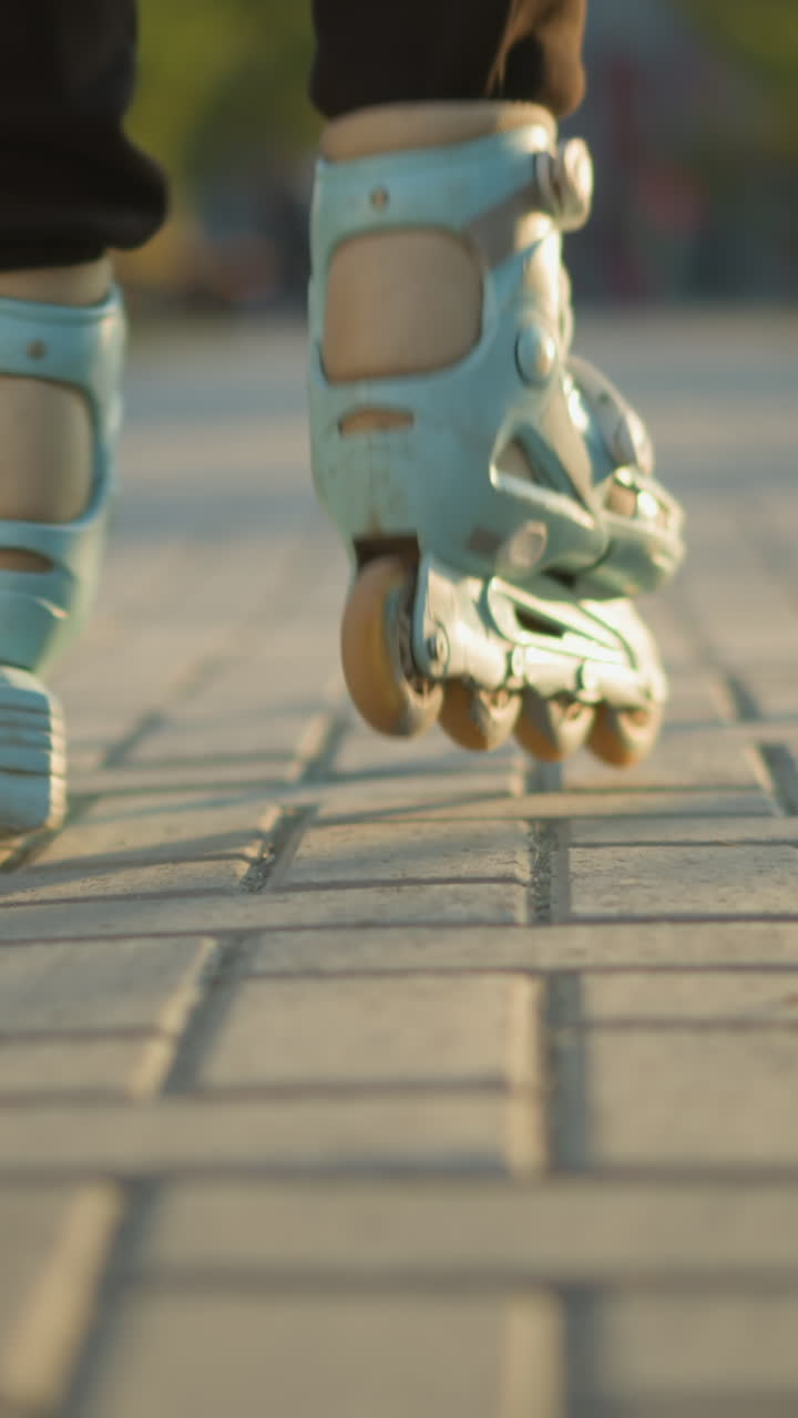 A back shot focusing on a person s feet wearing rollerblades as they glide smoothly along a paved path in a park. The background is softly blurred, drawing attention to the motion of the rollerblades