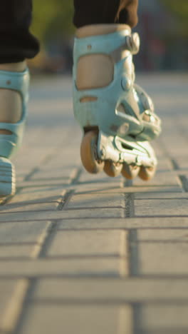 a back shot focusing on a person s feet wearing rollerblades as they glide smoothly along a paved path in a park. the background is softly blurred, drawing attention to the motion of the rollerblades