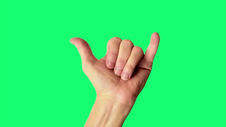 Primo piano di una mano maschile che fa il classico segno "hang loose", su uno sfondo verde ideale per il chroma key.