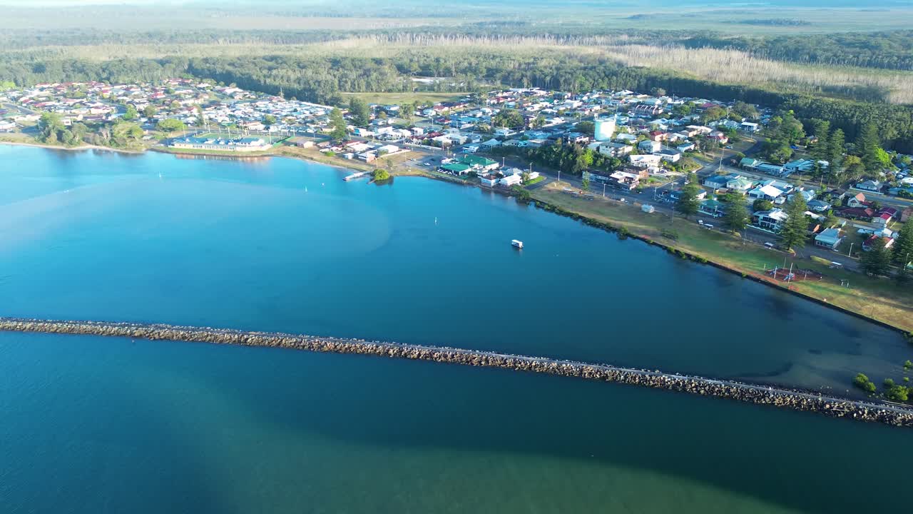 Drone aerial landscape of rural Harrington town housing along coastline suburb with river channel break wall and waterfront foreshore near Taree in NSW Australia travel tourism outdoors infrastructure