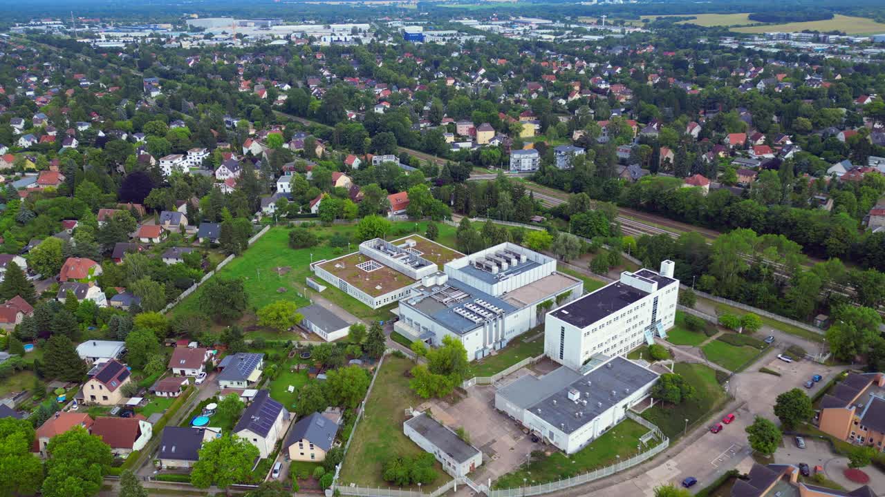 datacenter building with cooling system on the roof, surrounded by residential houses, showcasing urban and industrial integration. Magic aerial view flight drone camera pointing down