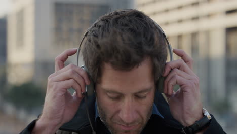 retrato de cerca joven empresario atractivo se pone auriculares disfrutando escuchando música estilo de vida urbano relajante en la ciudad el viento sopla en cámara lenta