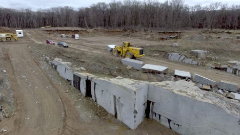 Construction-Front-Loader-Moving-a-Large-Piece-of-Granite-on-a-Dirt-Road