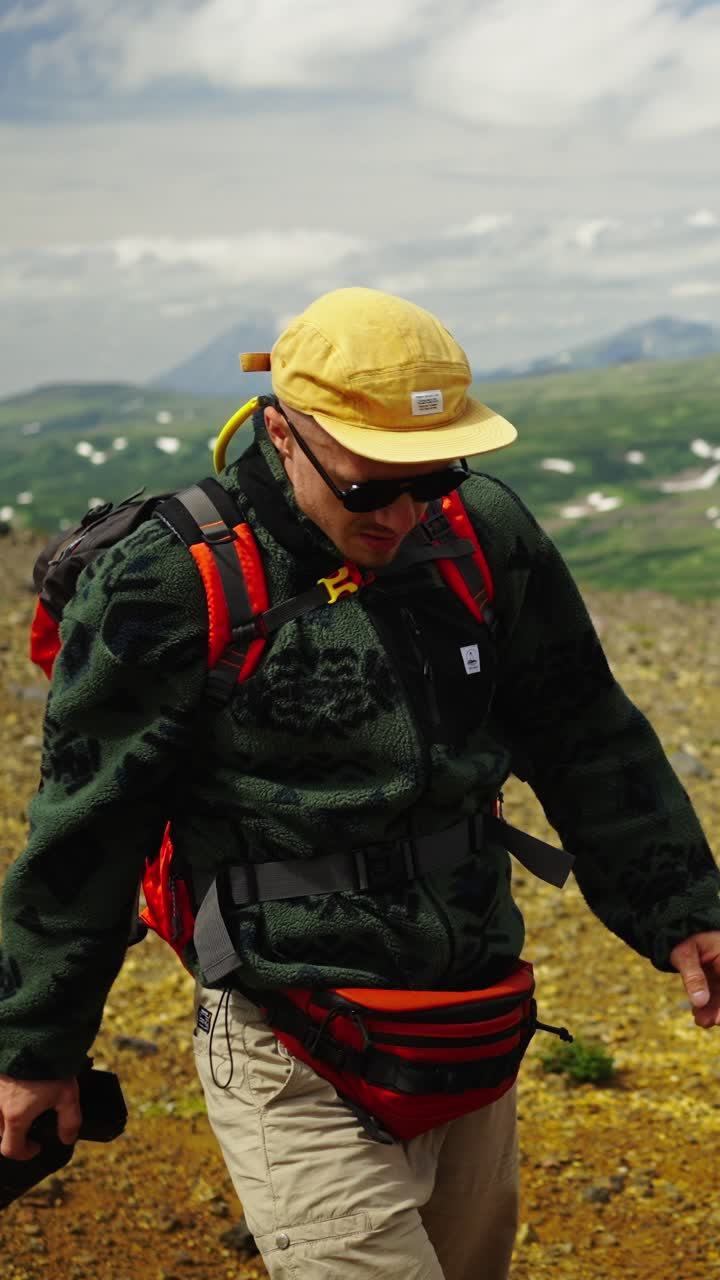 Escursionista con zaino e macchina fotografica che cammina in un paesaggio montano
