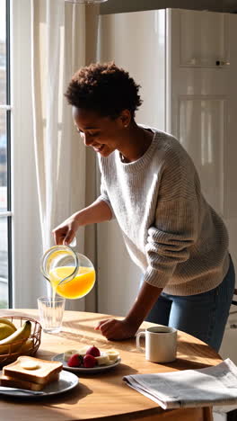 smiling woman pouring orange juice for breakfast