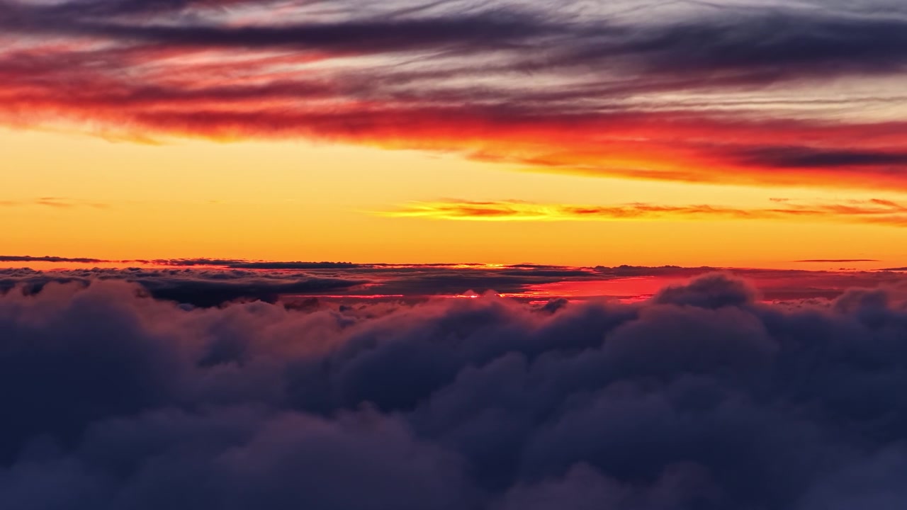 Dramatischer Sonnenuntergangshimmel mit roten und orangefarbenen Farbtönen über einer wogenden Wolkenlandschaft.