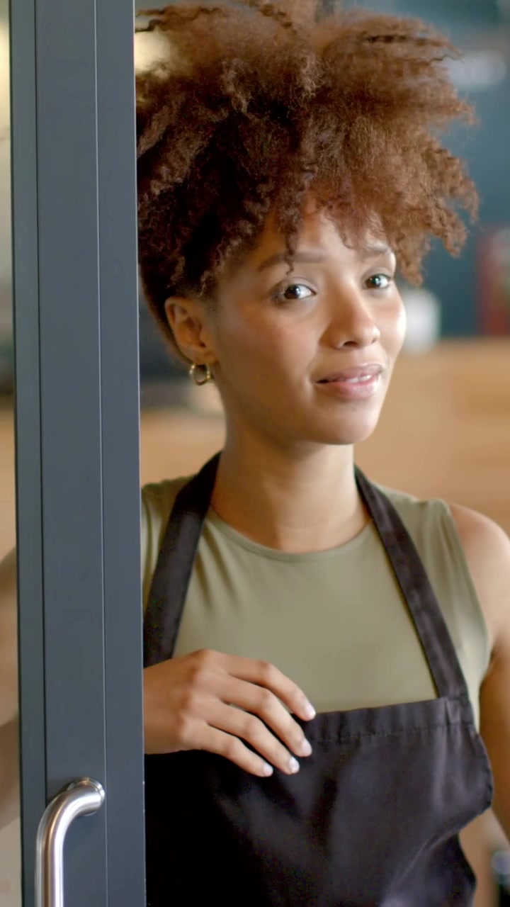 Hand grabbing right door handle, woman peeking and pushing glass door open, entering cafe to serve