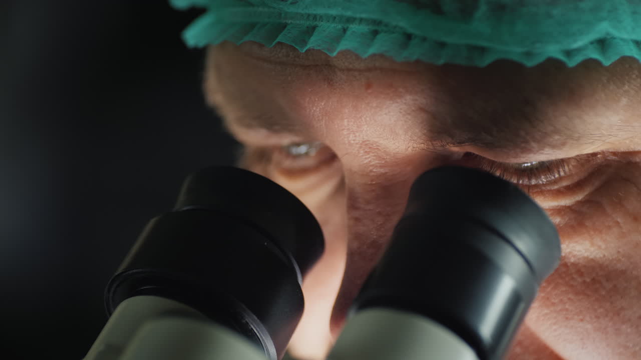 현미경의 접안렌즈를 들여다보는 남성 연구원의 얼굴