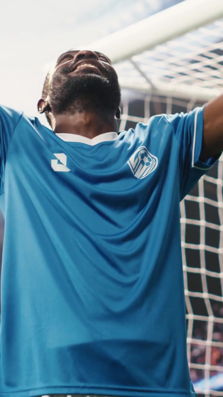 Video verticale: attaccante afroamericano che bacia il terreno per una celebrazione calcistica.