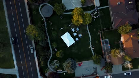 toma aérea a vista de pájaro de una recepción de bodas al aire libre en un patio trasero en un vecindario suburbano en un brillante y cálido día de verano
