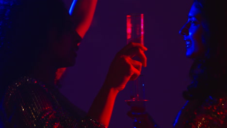 close up of two women in nightclub bar or disco dancing and drinking alcohol 2