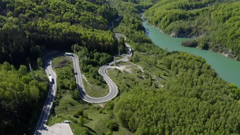 aerial view of curved asphalt road in lush green mountain by the teleajen river in maneciu, romania