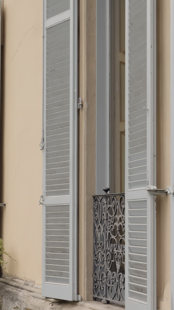 Architectural Details: Open Shutters and Wrought Iron Railing on a Building Facade
